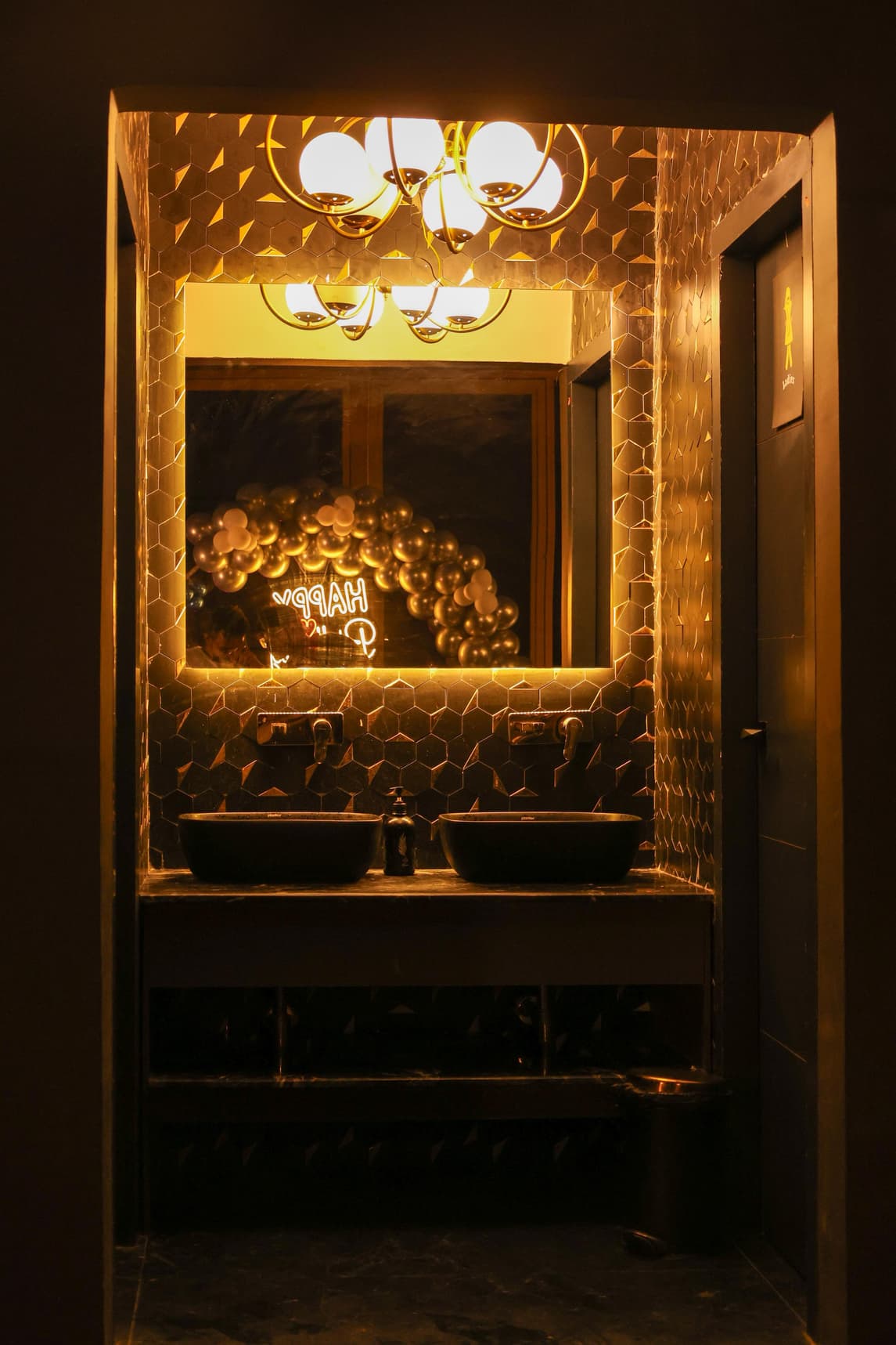 Elegant bar area with backlit gold arch shelving and glassware against a black marble wall.