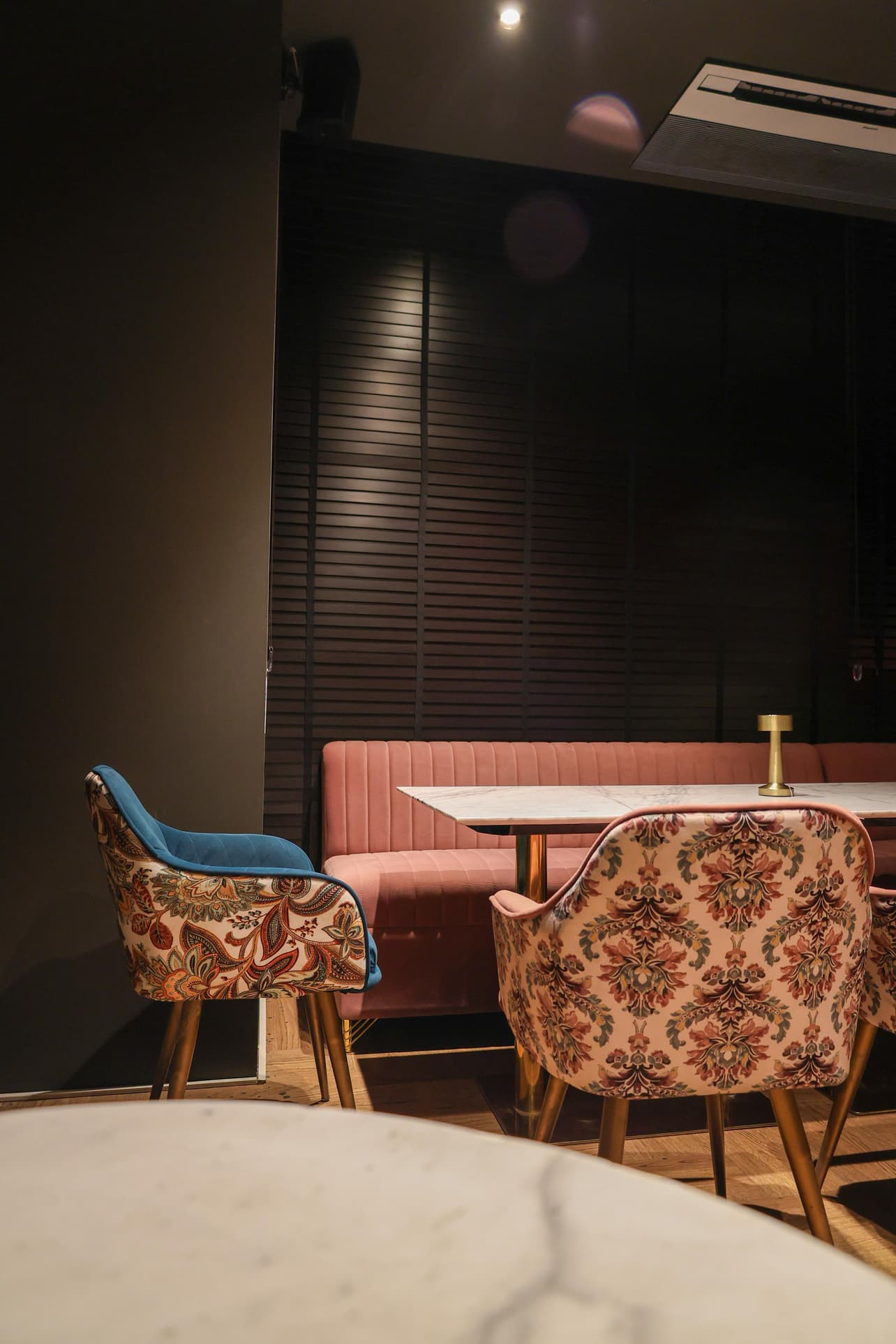 Dining area with marble-top tables and patterned velvet armchairs.