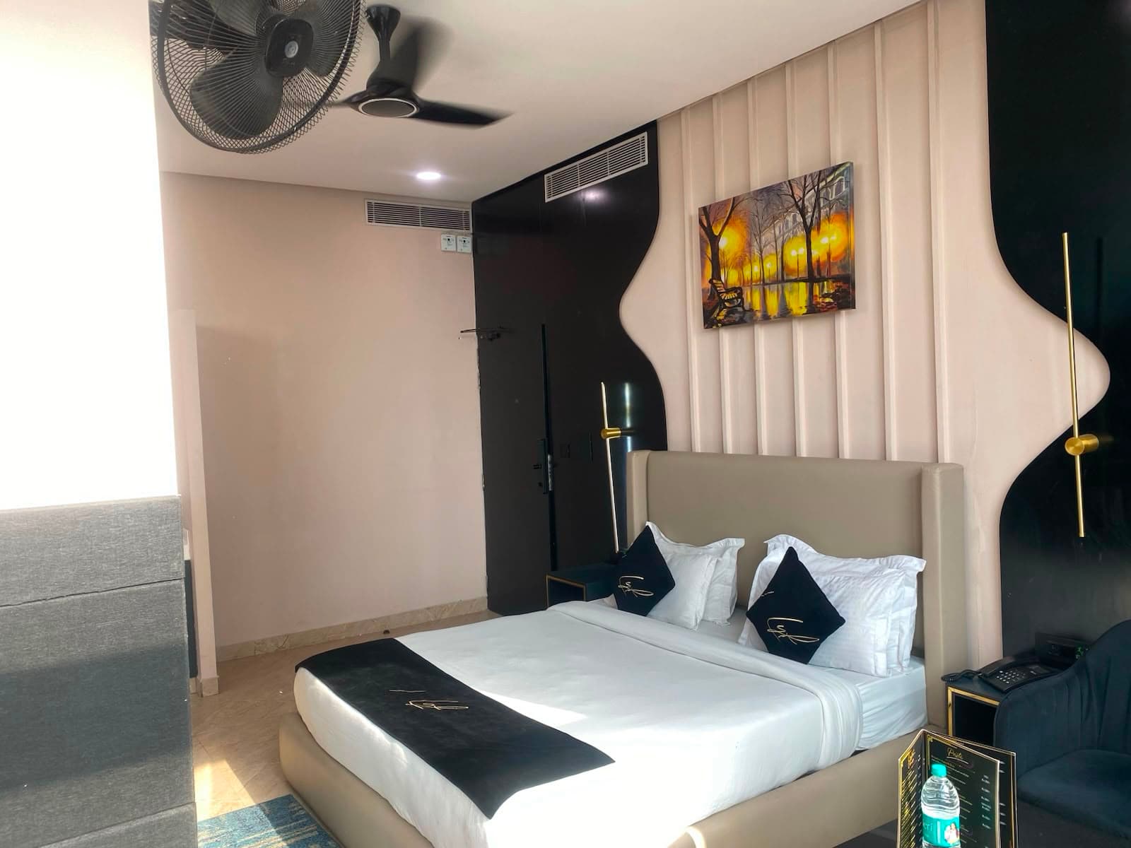 Sky Studio bedroom with black accent wall and gold reading light.